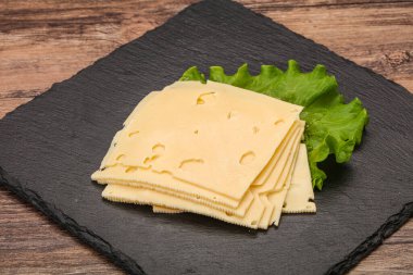 Salata yapraklarının üzerinde dilimlenmiş sarı peynir.