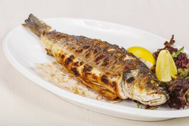 Izgara deniz kabuğu balığı limon ve salata servis etti.