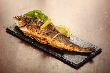 Izgara deniz kabuğu limon dilimi ve salata yaprakları servis edilir.