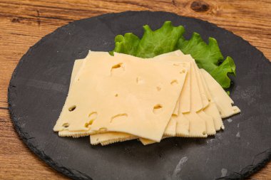 Salata yapraklarının üzerinde dilimlenmiş sarı peynir.