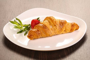 Tatlı kruvasan tabakta çilek servis edilir.