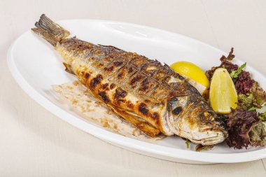 Izgara deniz kabuğu balığı limon ve salata servis etti.