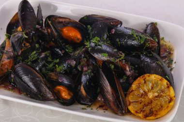 Lezzetli haşlanmış midye ve limon ile servis edilen otlar.