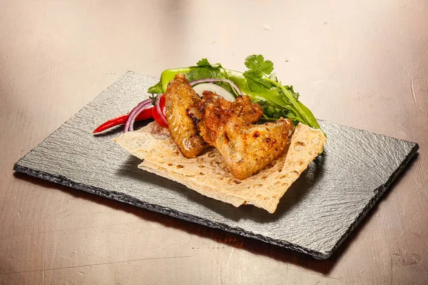 Izgara tavuk kanadı soğan ve kişniş servis edilir.