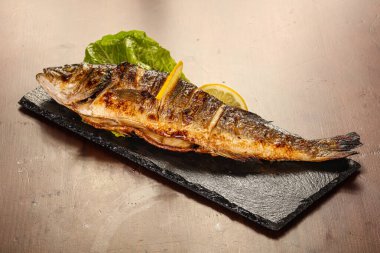 Izgara deniz kabuğu limon dilimi ve salata yaprakları servis edilir.