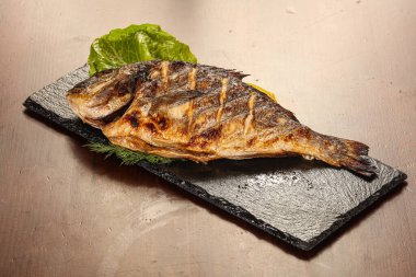 Izgara limon dilimi ve salata yaprakları.