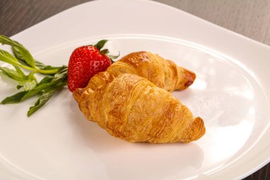 Tatlı kruvasan tabakta çilek servis edilir.