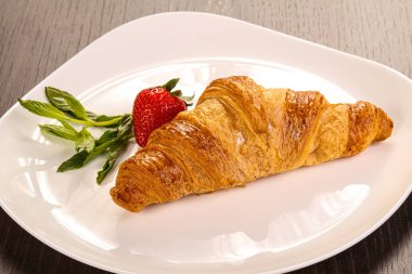 Tatlı kruvasan tabakta çilek servis edilir.