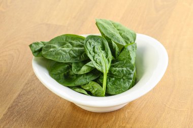 Tahta arka planda taze yeşil ıspanak yaprakları var.