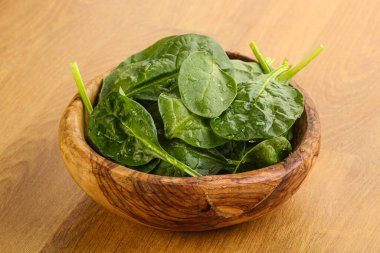 Tahta arka planda taze yeşil ıspanak yaprakları var.