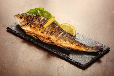 Izgara deniz kabuğu limon dilimi ve salata yaprakları servis edilir.