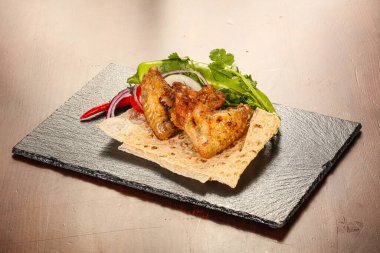 Izgara tavuk kanadı soğan ve kişniş servis edilir.