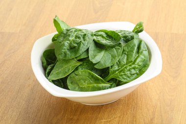 Tahta arka planda taze yeşil ıspanak yaprakları var.