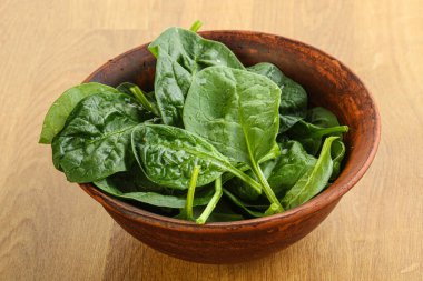 Tahta arka planda taze yeşil ıspanak yaprakları var.