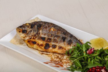 Kızarmış dorada balığı limon ve roka servis etti.