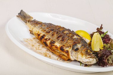 Izgara deniz kabuğu balığı limon ve salata servis etti.