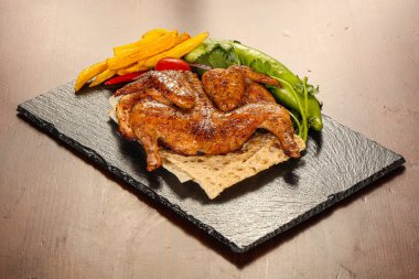 Kızarmış tavuk çeşitli sebze ve otlar sunar.