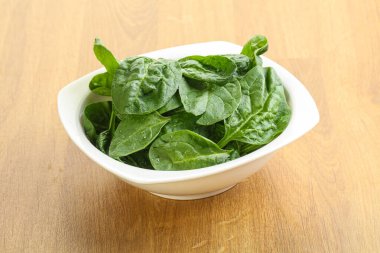 Tahta arka planda taze yeşil ıspanak yaprakları var.