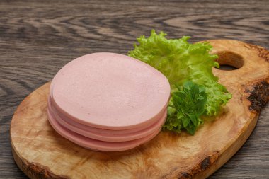 Dilimlenmiş domuz doğal sosisi güvertede fesleğen servis edilir.