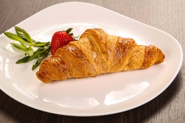 Tatlı kruvasan tabakta çilek servis edilir.