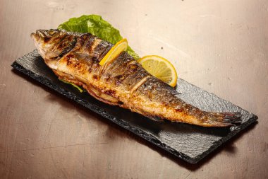 Izgara deniz kabuğu limon dilimi ve salata yaprakları servis edilir.