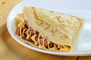 Dilimlenmiş sosis ve hardal soslu krep.