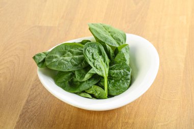 Tahta arka planda taze yeşil ıspanak yaprakları var.