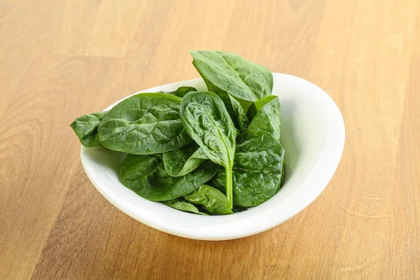 Tahta arka planda taze yeşil ıspanak yaprakları var.