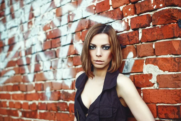 Kavkazské blonďatá žena stojící za cihlová zeď — Stock fotografie