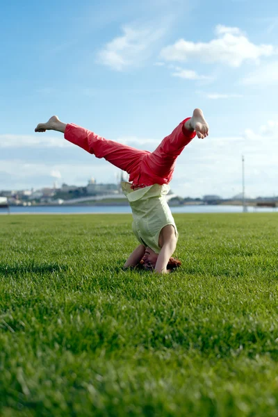 Piękna, młoda dziewczyna robi ćwiczenia rozciągające na zielonej trawie. — Zdjęcie stockowe
