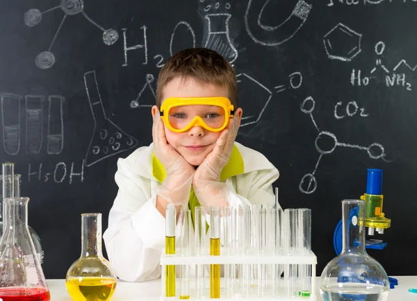 Schoolboy gown and gloves watching chemical experiment in tube — Stock Photo, Image