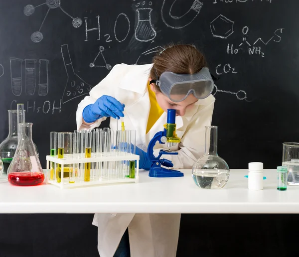 Schoolgirl in white gown doing experiments with liquids — Stock Photo, Image