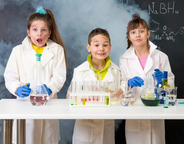 Drei aufgeregte lustige Kinder nach Chemie-Experiment im Labor — Stockbild Drei aufgeregte Kinder nach chemischem Experiment — Stockfoto