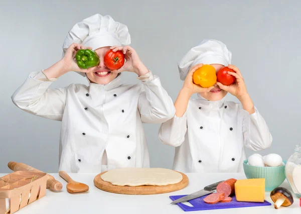 Мальчик и девочка в белой форме за столом готовят пиццу — стоковое фото