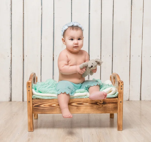 Játékos kis gyermek ágyon ül — Stock Fotó