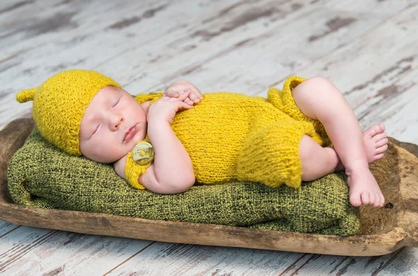 Bebé recién nacido en traje amarillo durmiendo en una cuna de madera — Foto de Stock