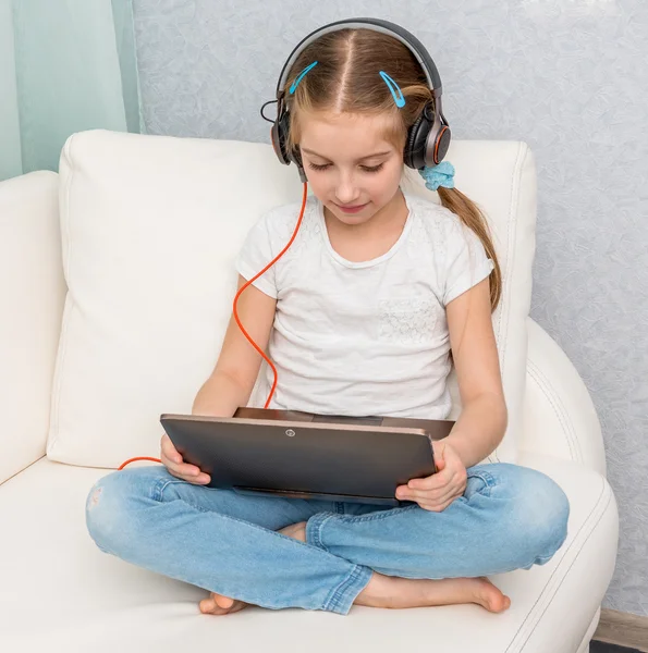 Smiling little girl listening something with headphones — Stock Photo, Image