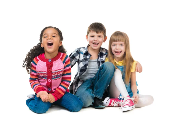 Tres niños alegres sentados en el suelo en un estudio — Foto de Stock