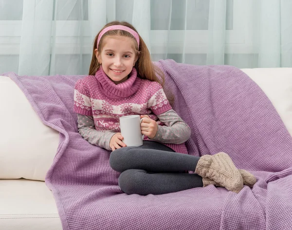 Jolie petite fille sur un canapé avec couverture chaude — Photo
