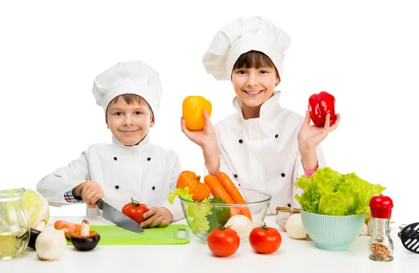 Pequenos chefs por mesa com legumes — Fotografia de Stock