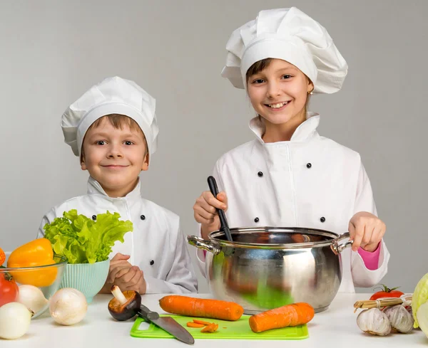 Dois pequenos chefs cozinham e sorriem — Fotografia de Stock