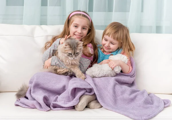 Two lovely little girls embracing on sofa — Stock Photo, Image