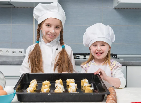 Two little girls in chef uniform with ingredients on table — Stock Photo, Image