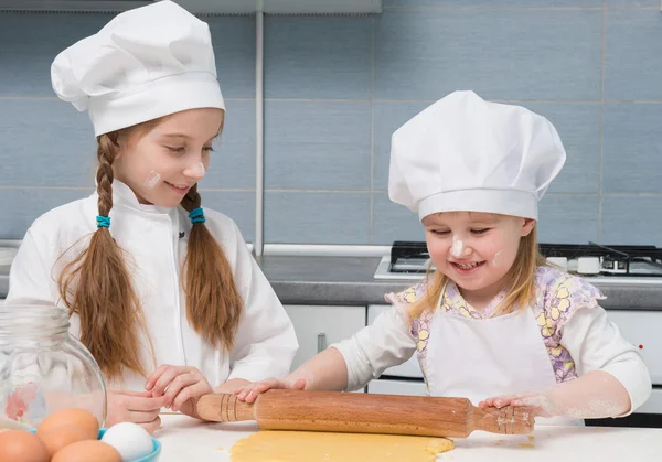 Two little girls in chef uniform sheeted dough — Stock Photo, Image