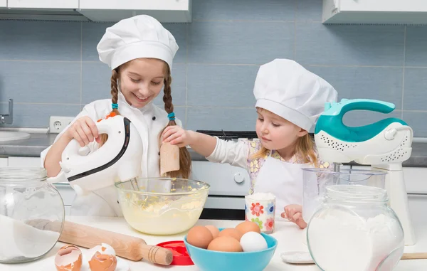 Duas meninas em uniforme de chef com ingredientes na mesa — Fotografia de Stock