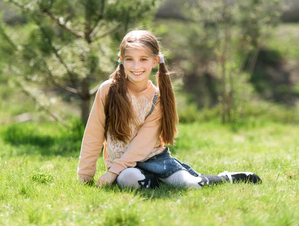 可爱微笑的小女孩坐在草地上 — 图库照片