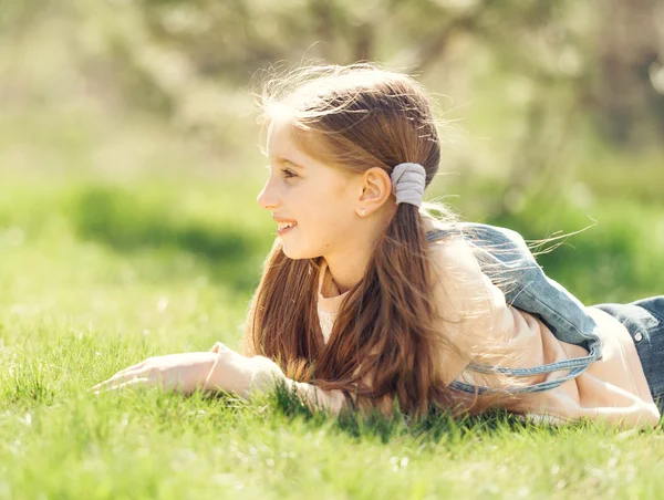 Schattig lachende klein meisje liggend op het gras — Stockfoto