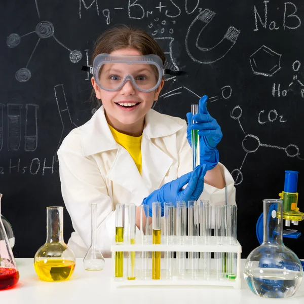 Schülerin im weißen Kittel experimentiert im Chemielabor mit Flüssigkeiten — Stockbild Schülerin im weißen Gewand experimentiert mit Flüssigkeiten — Stockfoto
