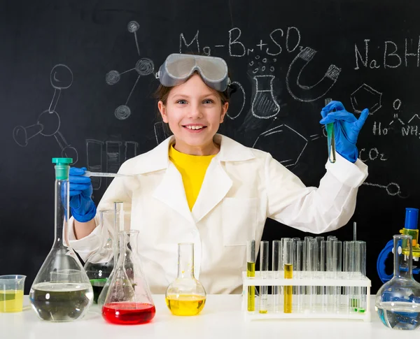 Schülerin im weißen Kittel experimentiert im Chemielabor mit Flüssigkeiten — Stockbild Schülerin im weißen Gewand experimentiert mit Flüssigkeiten — Stockfoto