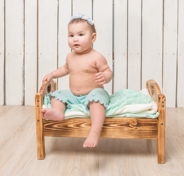 Lekfull lilla barnet sitter på en barnsäng — Stockfoto